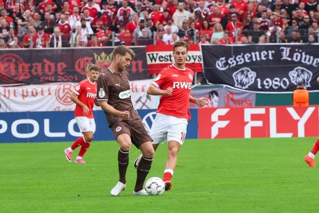 Marvin Obuz ( 10; Rot-Weiss Essen) behauptet den Ball im Zweikampf gegen einen Spieler des FC St. Pauli vor der voll besetzten Heimkurve im Stadion an der Hafenstraße. Im Hintergrund läuft ein weiterer Rot-Weiss-Spieler ins Bild. Marvin Obuz ( 10; Rot-Weiss Essen) im Zweikampf gegen FC St. Pauli *** Marvin Obuz, No. 10 for Rot-Weiss Essen, holds onto the ball in a one-on-one battle against an FC St. Pauli player in front of the packed home stands at the Stadion an der Hafenstraße. In the background, another Rot-Weiss player runs into the frame. Marvin Obuz, No. 10 for Rot-Weiss Essen, in a one-on-one battle against FC St. Pauli Copyright: xRuhr.Pottraitx