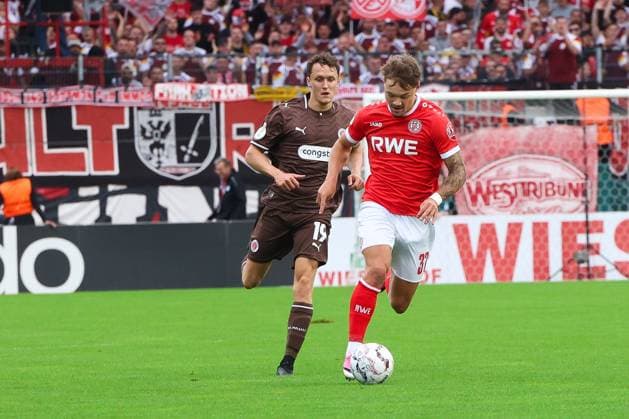 Jannik Hofmann von Rot-Weiss Essen führt den Ball am Fuß und setzt sich gegen Martijn Kaars vom FC St. Pauli durch. Die Szene findet vor der vollbesetzten Westtribüne im Stadion an der Hafenstraße in Essen statt. Jannik Hofmann ( 37; Rot-Weiss Essen) im Zweikampf gegen Martijn Kaars *** Jannik Hofmann of Rot Weiss Essen dribbles the ball and beats Martijn Kaars of FC St. Pauli. The scene takes place in front of the packed West Stand at the stadium on Hafenstraße in Essen. Jannik Hofmann (No. 37, Rot Weiss Essen) in a tackle against Martijn Kaars. Copyright: xRuhr.Pottraitx