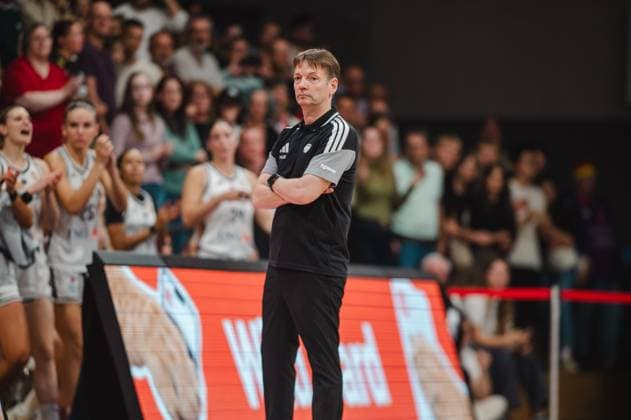 Ein Trainer der deutschen Damen-Nationalmannschaft steht mit verschränkten Armen an der Seitenlinie der Sparkassen-Arena in Göttingen und verfolgt konzentriert das Spielgeschehen. Im Hintergrund jubeln Spielerinnen des deutschen Teams und die Zuschauertribünen sind gut gefüllt. Trainer Deutschland Damen Basketball beobachtet das Spiel in Göttingen *** A coach for the German women s national team stands with his arms crossed on the sidelines at the Sparkassen Arena in Göttingen, intently watching the game. In the background, players from the German team are cheering, and the stands are well-filled. The coach of the German women s basketball team watches the game in Göttingen. Copyright: xJoelxKruehlerx