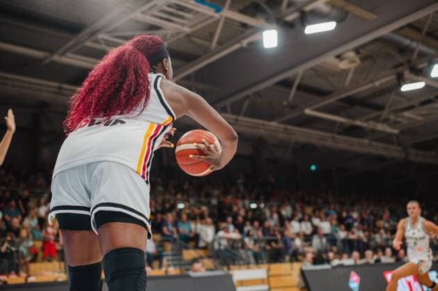 Eine Spielerin der deutschen Damen-Nationalmannschaft hält den Basketball und bereitet einen Pass oder Wurf vor, aufgenommen aus einer tiefen Froschperspektive hinter ihr. Im Hintergrund läuft eine weitere deutsche Spielerin, die Tribünen sind gut gefüllt. Deutschland A-Natio Damen mit Ball in der Sparkassen-Arena Göttingen *** A player on the German women s national team is holding the basketball and preparing to pass or shoot, photographed from a low frog s-eye view behind her. In the background, another German player is running; the stands are well-filled. Germany A Women s National Team with the ball at the Sparkassen Arena in Göttingen Copyright: xJoelxKruehlerx
