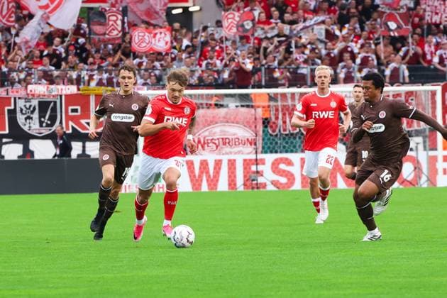 Jannik Hofmann von Rot-Weiss Essen treibt den Ball im Mittelfeld voran, flankiert von Janne Sietan ( 22; Rot-Weiss Essen) und Gegenspielern des FC St. Pauli. Im Hintergrund feuern die Fans der Heimmannschaft die Essener an. Jannik Hofmann (Rot-Weiss Essen) im Dribbling gegen FC St. Pauli *** Jannik Hofmann of Rot Weiss Essen drives the ball forward in midfield, flanked by Janne Sietan (No. 22, Rot Weiss Essen) and opponents from FC St. Pauli. In the background, the home team’s fans cheer on the Essen players. Jannik Hofmann of Rot Weiss Essen dribbles against FC St. Pauli. Copyright: xRuhr.Pottraitx