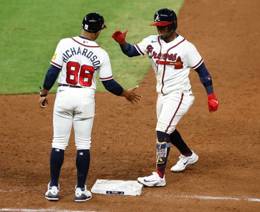 Second baseman Ozzie Albies 1 of the Atlanta Braves high fives first base coach Antoan Richardson 88 after hitting a go-ahead RBI single in the eighth inning against the Los Angeles Dodgers att Truist Park on Tuesday, August 25, 2026 in Atlanta, Georgia.  ATL20260825108 MikexZarrilli