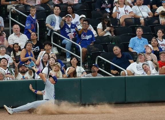 Left fielder Alex Call 12 of the Los Angeles Dodgers slides to make a catch in foul ground in the third inning against the Atlanta Braves at Truist Park on Tuesday, August 25, 2026 in Atlanta, Georgia.  ATL20260825117 MikexZarrilli