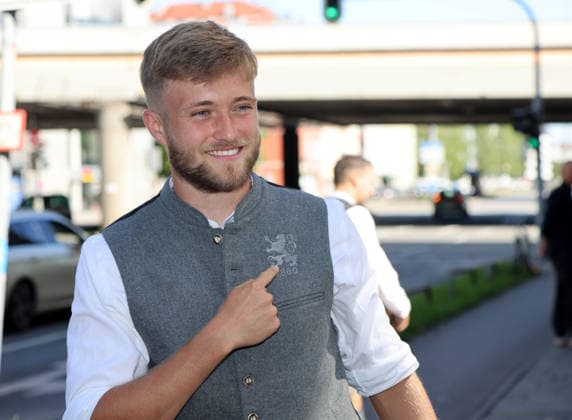 Fussball, Herren, Wiesn Einkleidung, Saison 2026 2027, TSV 1860 München, Trachten Angermaier Matthew Collins (TSV 1860 München) deutet auf das Logo mit dem Löwen und 1860, in Tracht, Lederhose