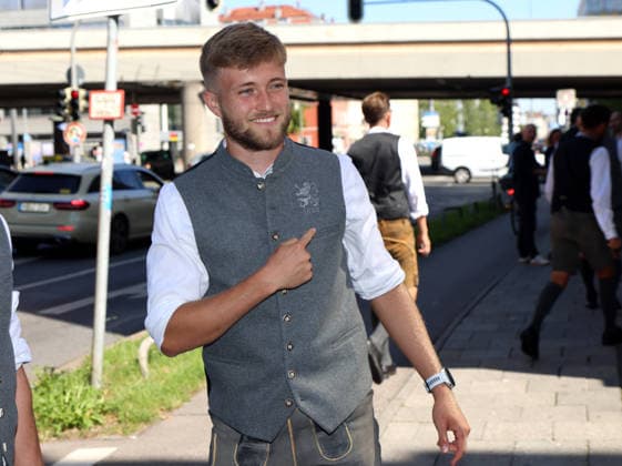 Fussball, Herren, Wiesn Einkleidung, Saison 2026 2027, TSV 1860 München, Trachten Angermaier Matthew Collins (TSV 1860 München) deutet mit dem Zeigefinger auf das Logo von 1860 und dem Löwen auf seiner Trachtenjacke in Tracht, Lederhose