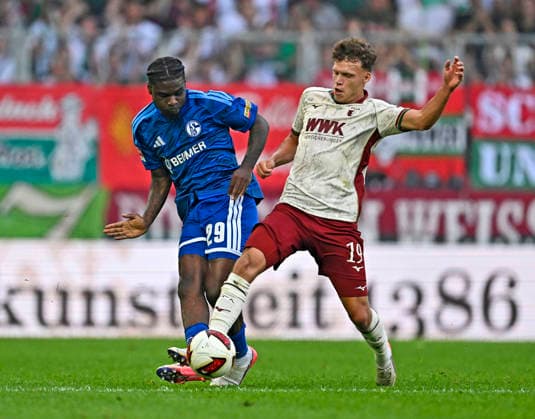 30.08.2026, Fussball Bundesliga 2026 2027, 1.Spieltag, FC Augsburg - FC Schalke 04, in der WWK-Arena Augsburg, v.l. Junior Dina Ebimbe (Schalke 04) gegen Robin Fellhauer (Augsburg) ***DFL and DFB regulations prohibit any use of photographs as image sequences and or quasi-video.*** *** August 30, 2026, 2026–2027 Bundesliga, Matchday 1, FC Augsburg vs. FC Schalke 04, at the WWK Arena in Augsburg, from left: Junior Dina Ebimbe (Schalke 04) vs. Robin Fellhauer (Augsburg) ***DFL and DFB regulations prohibit any use of photographs as image sequences and or quasi-video***