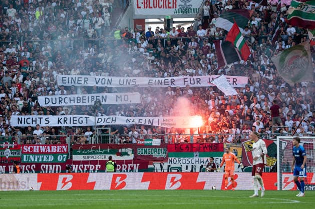 Fussball: Deutschland: 1. Bundesliga 2026 2027 - 1. Spieltag, 30.08.2026 - FC Augsburg vs. FC Schalke 04 (WWK Arena, Augsburg); Banner, Fankurve FC Augsburg, Fans *** Soccer Germany 1 Bundesliga 2026–2027, Matchday 1, August 30, 2026: FC Augsburg vs. FC Schalke 04 at WWK Arena, Augsburg; banners, FC Augsburg fan section, fans Copyright: xValentinxDomgjonix