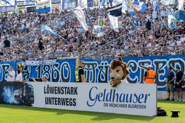 Maskottchen Sechzgerl (TSV 1860 Muenchen) hinter einer Werbebande Loewenstark Unterwegs Geldhauser die Muenchner Busreisen, dahinter die Westkurve mit den Loewenfans GER, TSV 1860 Muenchen vs. TSV Landsberg 1882, Fussball, Regionalliga Bayern, 6. Spieltag, Saison 2026 2027, 30.08.2026. (DFL DFB REGULATIONS PROHIBIT ANY USE OF PHOTOGRAPHS as IMAGE SEQUENCES and or QUASI-VIDEO). Foto: HMB Media Heike Feiner Copyright: HMBxMedia HeikexFeiner