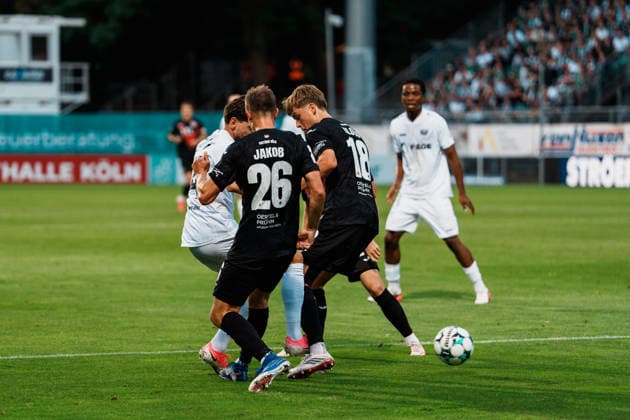 Deutschland: Fußball 3. Liga Männer 2026 - 2027, 3. Spieltag - FC Viktoria Köln vs SC Preußen Münster (Köln): Charalambos Makridis (SC Preußen Münster, 14) im Dribbling, Angriff, am Strafraum, Zweikampf gegen Kilian Jakob (FC Viktoria Köln, 26), Pascal Armando Fallmann (FC Viktoria Köln, 28), Lucas Mika Wolf (FC Viktoria Köln, 21) Copyright: xThiemoxRudolphx