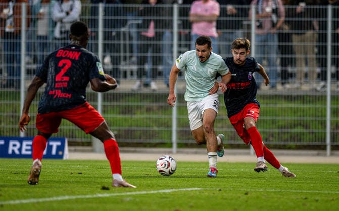 Fussball, Saison 2026 2027, Regionalliga West, 01.09.2026, 06. Spieltag, Herren, 1.FC Bocholt (mint) vs. Bonner SC (blau rot) v.l.: Massaman Keita (Bonner SC), Marvin Lorch (1.FC Bocholt), Julijan Popvic (Bonner SC), Bocholt Stadion am Huenting Deutschland
