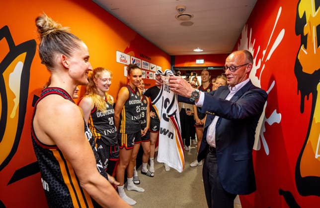Basketball Berlin 04.09.2026 FIBA Women™s Basketball World Cup Germany 2026 Vorrunde Gruppe Spanien (ESP) - Deutschland (GER) Bundeskanzler Friedrich Merz zu Gast Besuch der Deutschen Mannschaft nach dem Spiel vor der Kabine Leonie Fiebich (Deutschland, No.13) überreicht ihm ein unterschriebenes Trikot Frida Bühner (Deutschland, No.20) Clara Bielefeld (Deutschland, No.25) und andere