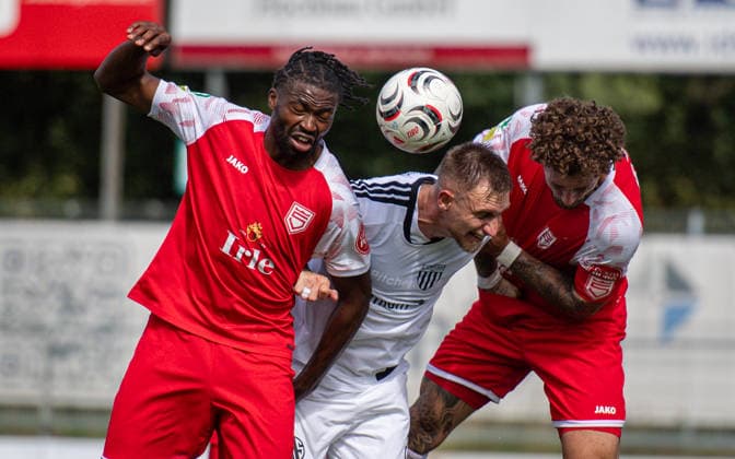 Fussball, Saison 2026 2027, Regionalliga West, 05.09.2026, 07. Spieltag, Herren, 1.FC Bocholt (weiss) vs. Sportfreunde Siegen (rot) v.l.: Matono-Glody Ngyombo (SF Siegen), Alexander Hahn (1.FC Bocholt), Jan-Luca Rumpf (SF Siegen), Bocholt Stadion am Huenting Deutschland