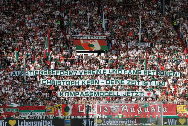 Banner von Fans Team (FC Augsburg), Kompassmodell beim Spiel zwischen FC Augsburg v Bayer 04 Leverkusen, Fussball, Herren, Bundesliga, 2026 2027, 3.Spieltag am 12.09.2026 in Augsburg, WWK ARENA. DFL and DFB regulations prohibit any use of photographs as image sequences and or quasi-video. Bayern Deutschland *** Banner by FC Augsburg fans, compass model at the match between FC Augsburg and Bayer 04 Leverkusen, soccer, men’s, Bundesliga, 2026–2027, Matchday 3 on September 12, 2026, in Augsburg, WWK ARENA. DFL and DFB regulations prohibit any use of photographs as image sequences and or quasi-video. Bavaria, Germany