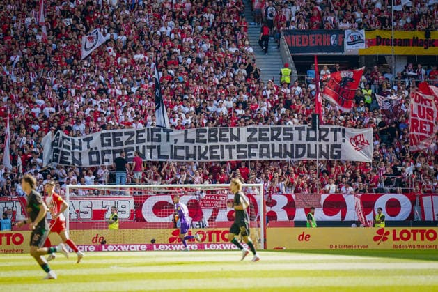 Deutschland: Fussball Bundesliga 2026 - 2027, 3. Spieltag - SC Freiburg vs Borussia Mönchengladbach - Europa-Park-Stadion (Freiburg): Fans des SC Freiburg auf der Tribüne mit großem Spruchband Gesicht gezeigt, Leben zerstört! Gegen Öffentlichkeitsfahndung. Fanprotest gegen Öffentlichkeitsfahndung, Fahndungsfotos, Polizei, Strafverfolgung, Datenschutz, Persönlichkeitsrechte, Fans, Zuschauer, Fankurve, Transparent, Spruchband, Protestbanner, Fahnen, Stadion. *** Germany Soccer Bundesliga 2026–2027, Matchday 3: SC Freiburg vs. Borussia Mönchengladbach at Europa-Park Stadium in Freiburg. SC Freiburg fans in the stands holding a large banner reading: Face Revealed, Life Destroyed. Protest against public wanted notices. Fan protest against public wanted notices, Wanted photos, police, criminal prosecution, data protection, personal rights, fans, spectators, fan section, banner, protest banner, flags, stadium Copyright: xJOERANxSTEINSIEKx