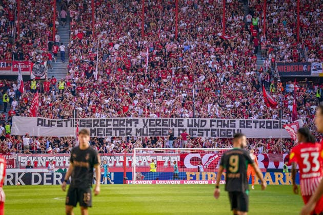 Deutschland: Fussball Bundesliga 2026 - 2027, 3. Spieltag - SC Freiburg vs Borussia Mönchengladbach - Europa-Park-Stadion (Freiburg): Fans des SC Freiburg auf voll besetzter Tribüne mit großem Spruchband Aufstieg reform? Vereine und Fans betrogen! Meister müssen aufsteigen!. Fanprotest, Aufstiegsreform, Regionalliga, Aufstiegsregelung, DFB, Fußball, Fans, Ultras, Zuschauer, Fankurve, Transparent, Spruchband, Protestbanner, Stadion, SC Freiburg. *** Germany Soccer Bundesliga 2026–2027, Matchday 3: SC Freiburg vs. Borussia Mönchengladbach at Europa-Park Stadium in Freiburg. SC Freiburg fans in a packed stands holding a large banner reading: Promotion Reform—Clubs and Fans Betrayed—Champions Must Be Promoted. Fan protest, promotion reform, Regionalliga, promotion rules, DFB, soccer, fans, ultras, spectators, fan section, banner, protest banner, stadium, SC Freiburg Copyright: xJOERANxSTEINSIEKx