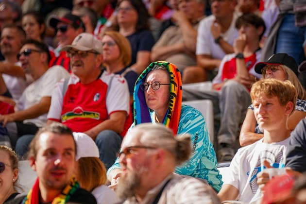 Deutschland: Fussball Bundesliga 2026 - 2027, 3. Spieltag - SC Freiburg vs Borussia Mönchengladbach - Europa-Park-Stadion (Freiburg): Zuschauerin auf der Tribüne schützt sich bei starker Sonneneinstrahlung mit einem bunten Fanschal über dem Kopf vor der Hitze. Fußball, Fans, Zuschauer, Tribüne, Sommer, Sonne, Hitze, Hitzeschutz, Sonnenschutz, hohe Temperaturen, heißes Wetter, Klimawandel, Hitzewelle, Stadion, SC Freiburg, Symbolfoto. *** German Soccer Bundesliga 2026–2027, Matchday 3: SC Freiburg vs. Borussia Mönchengladbach at Europa-Park Stadium in Freiburg. A female spectator in the stands protects herself from the heat and strong sunlight by draping a colorful fan scarf over her head. Soccer, fans, spectators, stands, summer, sun, heat, heat protection, sun protection, high temperatures, hot weather, climate change, heat wave, stadium, SC Freiburg, stock photo Copyright: xJOERANxSTEINSIEKx