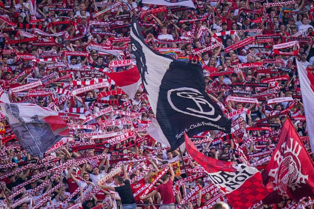 Deutschland: Fussball Bundesliga 2026 - 2027, 3. Spieltag - SC Freiburg vs Borussia Mönchengladbach - Europa-Park-Stadion (Freiburg): Fans des SC Freiburg auf voll besetzter Tribüne halten rot-weiße Fanschals und schwenken große Vereinsfahnen mit SC-Freiburg-Wappen. Fans, Zuschauer, Fankurve, Heimfans, Ultras, Fahnenmeer, Fanschal, Support, Stimmung, Fankultur, SC Freiburg, Vereinslogo, Fußball, Bundesliga, Stadion, Tribüne. *** Germany Soccer Bundesliga 2026–2027, Matchday 3: SC Freiburg vs. Borussia Mönchengladbach at Europa-Park Stadium, Freiburg. SC Freiburg fans in a packed stands hold red-and-white scarves and wave large club flags bearing the SC Freiburg crest. Fans, spectators, fan section, home fans, ultras, sea of flags, fan scarf, support, atmosphere, fan culture, SC Freiburg, club logo, soccer, Bundesliga, stadium, stands Copyright: xJOERANxSTEINSIEKx