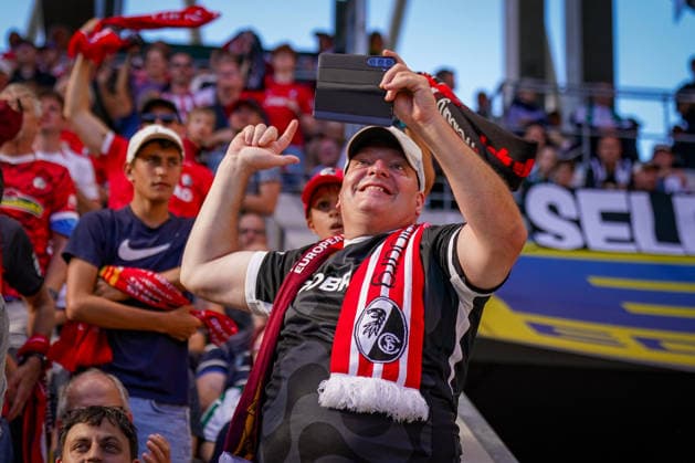 Deutschland: Fussball Bundesliga 2026 - 2027, 3. Spieltag - SC Freiburg vs Borussia Mönchengladbach - Europa-Park-Stadion (Freiburg): Fan des SC Freiburg reagiert begeistert auf die Tabellenführung und hält sein Smartphone hoch, nachdem der SC Freiburg die Bundesliga-Spitze übernimmt. Freude, Jubel, Emotionen, Spitzenreiter, Tabellenführer, Platz 1, Bundesliga-Tabelle, SC Freiburg, Fans, Zuschauer, Fanschal, Smartphone, Stadion, Fankultur. *** Germany Soccer Bundesliga 2026–2027, Matchday 3: SC Freiburg vs. Borussia Mönchengladbach at Europa-Park Stadium in Freiburg. An SC Freiburg fan reacts enthusiastically to the team’s rise to the top of the standings and holds up his smartphone after SC Freiburg takes the lead in the Bundesliga. Joy, Jubilation, Emotions, Top Team, League Leaders, 1st Place, Bundesliga Standings, SC Freiburg, Fans, Spectators, Fan Scarf, Smartphone, Stadium, Fan Culture Copyright: xJOERANxSTEINSIEKx