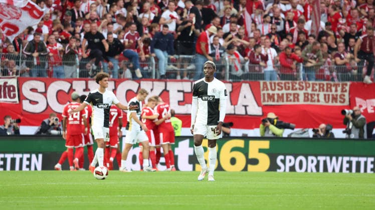 13.09.2026, xrekx, Fussball 1.Bundesliga, SV Elversberg - FC Bayern München v.l. David Mokwa (SV 07 Elversberg) enttaeuscht, enttäuscht, schaut enttaeuscht, niedergeschlagen, disappointed Torjubel nach dem Tor zum celebrating the goal celebrate 1:2 durch Harry Kane (FC Bayern Muenchen) (DFL DFB REGULATIONS PROHIBIT ANY USE OF PHOTOGRAPHS as IMAGE SEQUENCES and or QUASI-VIDEO) Elversberg