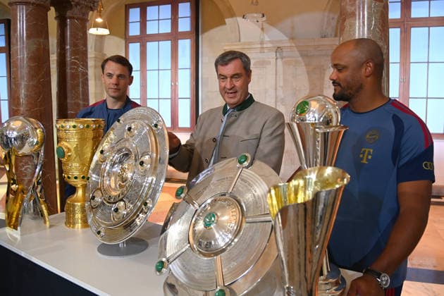 v.li:Manuel NEUER (Torwart Bayern Muenchen), Markus SOEDER (Ministerpraesident Bayern und CSU Vorsitzender), Trainer Vincent KOMPANY (Bayern Muenchen) stehen hinter den gewonnenen Pokalen,Pokal,Cup,Trophaee der Saison 2025 26 ,Meisterschale,Schale,DFB Pokal,Super Cup. Markus SOEDER (Ministerpraesident Bayern und CSU Vorsitzender) empfaengt die Meistermannschaften des FC Bayern Muenchen im Kuppelsaal in der Staatskanzlei in Muenchen am 16.09.2026.