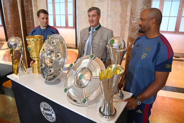 v.li:Manuel NEUER (Torwart Bayern Muenchen), Markus SOEDER (Ministerpraesident Bayern und CSU Vorsitzender), Trainer Vincent KOMPANY (Bayern Muenchen) stehen hinter den gewonnenen Pokalen,Pokal,Cup,Trophaee der Saison 2025 26 ,Meisterschale,Schale,DFB Pokal,Super Cup. Markus SOEDER (Ministerpraesident Bayern und CSU Vorsitzender) empfaengt die Meistermannschaften des FC Bayern Muenchen im Kuppelsaal in der Staatskanzlei in Muenchen am 16.09.2026.