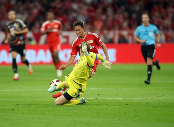 Fussball, Herren, Bundesliga, Saison 2026 2027, FC Bayern München - 1. FC Union Berlin, Allianz Arena Manuel Neuer (FC Bayern München) klärt in letzter Sekunde den Ball vor Woo-yeong Jeong (1.FC Union Berlin) mit einer Grätsche DFB, DFL regulations prohibit any use of photographs as image sequences and or quasi-video