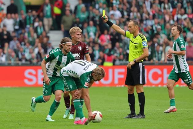 19.09.26, GER, Fussball, 1.FBL Männer, 4. Spieltag, Saison2026 2027, SV Werder Bremen vs. FC Augsburg Gelb die Gelbe Karte Schiedsrichter Bastian Dankert zeigt Hennes Behrens (FC Augsburg 16) die Gelbe Karte Bremen Weserstadion Bremen Germany Copyright: xnordphotoxGmbHx xTauchnitzx