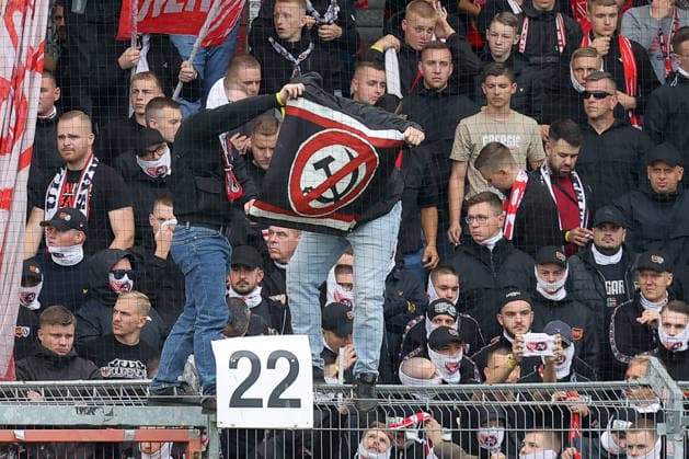 20.09.2026, xtgx, Fussball 2. Bundesliga, FC Energie Cottbus - FC St. Pauli, v.l. Cottbus Fans zeigen durchgestrichenes Hammer und SIchel Wappen, Kommunismus, Sozialismus (DFL DFB REGULATIONS PROHIBIT ANY USE OF PHOTOGRAPHS as IMAGE SEQUENCES and or QUASI-VIDEO) Cottbus
