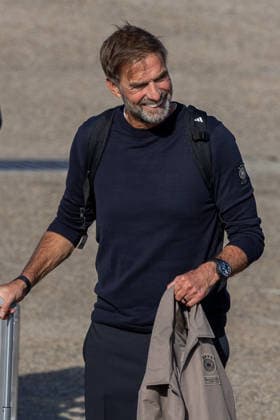 Abflug der deutschen DFB Fußball-Nationalmannschaft nach Amsterdam für dasNations-League Spiel gegen Niederlande, Nürnberg, 23.09.2026 Nationaltrainer Jürgen Klopp lächelt beim Abflug der deutschen Fußball-Nationalmannschaft nach Amsterdam. Er trägt einen Rucksack sowie eine Jacke mit DFB-Logo über dem Arm und steht neben einem Koffer auf dem Vorfeld. Nürnberg Bayern Deutschland