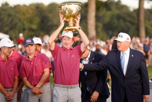 US Team Captain Brandt Snedeker raises the winners trophy with President Donald Trump after the United States team defeated the International Team 15.5 to 12.5 in the 2026 Presidents Cup at Medinah Country Club in Chicago, Illinois, on Sunday, September 27, 2026.  CHI20260927855 TANNENxMAURY