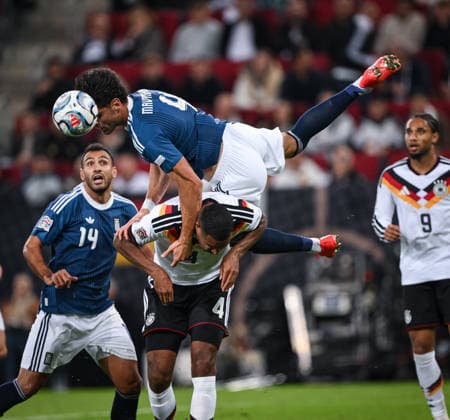 FUSSBALL UEFA Nations League Liga A Gruppe 2 2026 2027 in Augsburg 27.09.2026 Deutschland - Griechenland Ntinos Mavropanos (oben, Griechenland) fliegt ueber Jonathan Tah (unten, Deutschland) beobachtet von Vangelis Pavlidis (li, Griechenland)