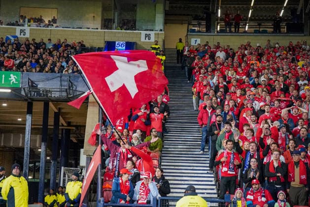 Fussball UEFA Nations League 2026 - 2027, 2. Spieltag - Schottland vs Schweiz - Hampden Park (Glasgow): Schweizer Fans auf der Tribüne im Hampden Park beim UEFA-Nations-League-Spiel Schottland gegen Schweiz. Im dicht besetzten Gästeblock wird eine große Schweizer Fahne geschwenkt, zahlreiche Fans tragen rote Nationaltrikots und Fanschals. Fussball, Schweiz, Fans, Zuschauer, Gästefans, Gästeblock, Tribüne, Schweizer Fahne, Nationalflagge, Fankultur, Stimmung, Supporter, Hampden Park, Glasgow. Copyright: xJOERANxSTEINSIEKx