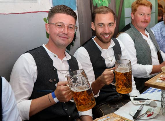 Fussball, Herren, Regionalliga Bayern, Saison 2026 2027, TSV 1860 München, Offizieller Wiesnbesuch, Hacker Festzelt Vincent Saller, Co-Trainer (TSV 1860 München) (li.) mit Michael Eberwein (TSV 1860 München) (re.) sitzend mit einer Maß Bier in der Hand, Tracht