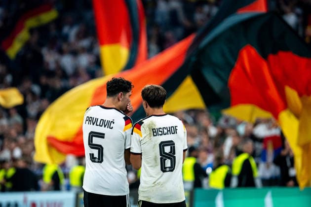 01.10.2026, GER, Fussball, Herren, UEFA Nations League Länderspiel, Liga A, 3. Spieltag, Deutschland vs. Serbien Aleksandar Pavlovic ( Deutschland, 5 ), Tom Bischof ( Deutschland, 8 ), dahinter Fans Zuschauer mit Fahnen München Allianz Arena Bayern Deutschland Copyright: xNordphoto Memmlerx