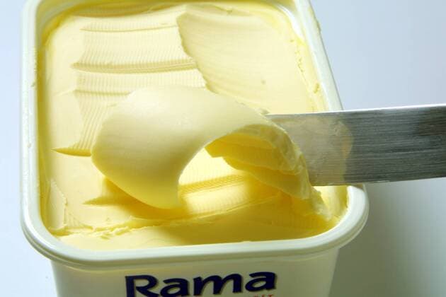 Messer fährt durch Margarine im Becher
