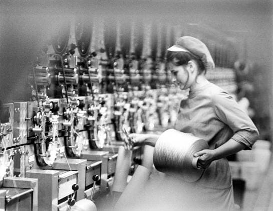 Arbeiterin entfernt die fertige Garnrolle im VEB-Chemiefaserkombinat Guben - DDR