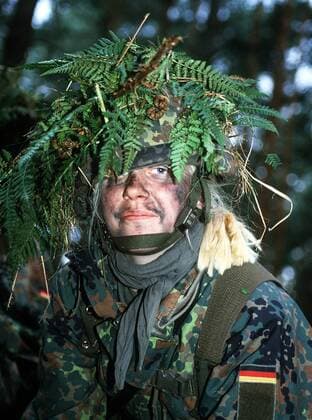 Getarnte Bundeswehrsoldatin während einer Geländeübung im Wald bei Dülmen