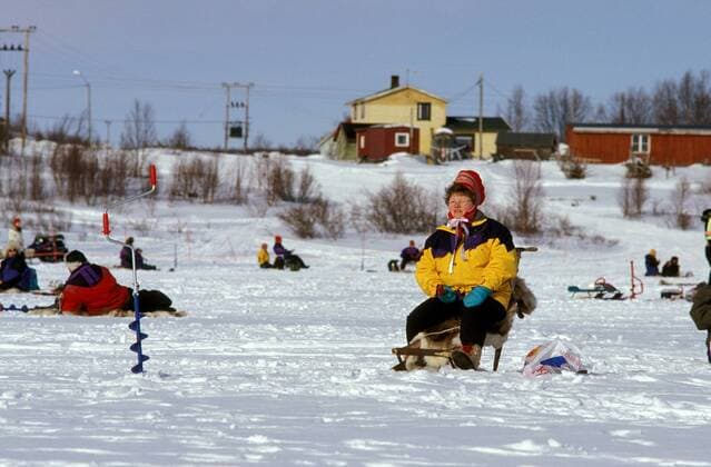 Frau angelt auf einem zugefrorenen See - Eisangelwettbewerb zu Ostern in Kautokeino