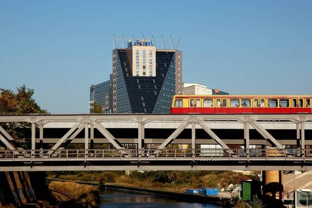 S-Bahn fährt über eine Brücke, dahinter das Estrel Hotel in Berlin-Neukölln