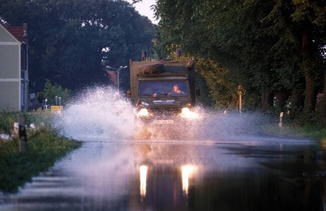 LKW der Bundeswehr stiebt durch das Wasser auf einer vom Hochwasser überfluteten Straße bei Pirna