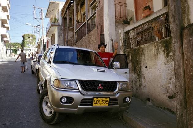 Sänger Eliades Ochoa (CUB) mit seinem parkenden Mitsubishi Nativa in einer Straße in Santiago de Cuba