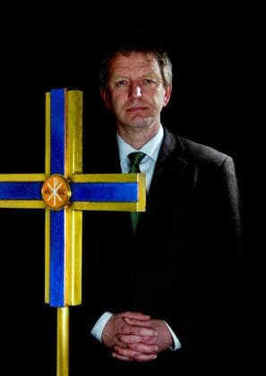 Jochen Bohl (GER Oberkirchenrat Landesbischof der Evangelischen Kirche in Sachsen) mit gefalteten Händen neben einem Kreuz