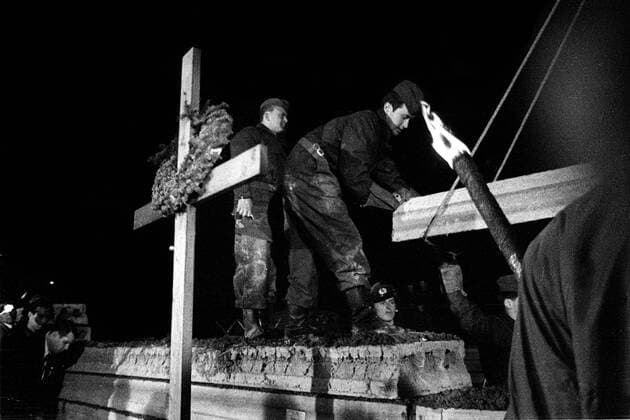 Aufstockung der Berliner Mauer hinter einem Gedenkkreuz