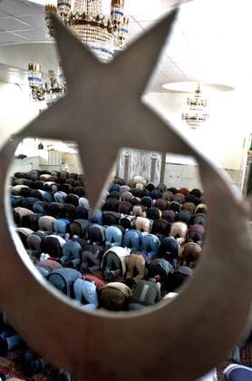 Gläubige türkische Moslems während des Freitagsgebets in einer Moschee in Recklinghausen - Durchblick durch das türkische Nationalsymbol Stern und Halbmond