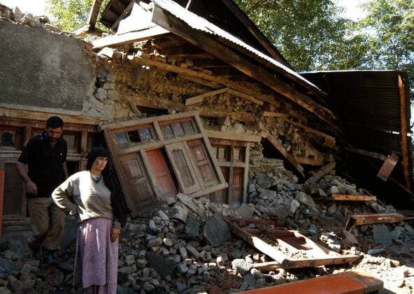 Ehepaar neben ihrem vom Erdbeben zerstörten Wohngebäude in Karnah - Indien 