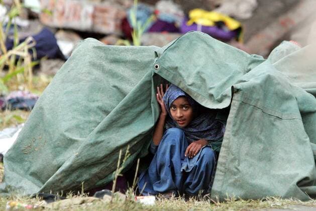 Junges Mädchen sucht nach dem katastrophalen Erdbeben in Balacot in Azad Kashmir Schutz unter einer Plane - 