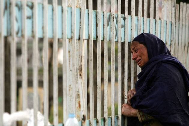 Verzweifelte Frau trauert um ihre beim schweren Erdbeben in Muzaffarabad getöteten Angehörigen vor dem Eingang eines Friedhofs - Pakistan - 