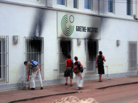Passanten vor dem Goethe Institut mit Brandschaden in Lome - Togo