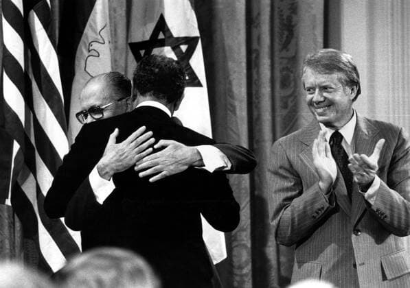 Präsident Jimmy Carter (re., USA) applaudiert während der Umarmung von Premierminister Menachem Begin (li., ISR) und Präsident Anwar as-Sadat (EGY) anlässlich der Unterzeichnung des Friedensvertrages von Camp David -  (CART2002101516)