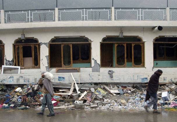 Pakistani vor einem stark beschädigten Haus nach dem Erdbeben in Balakot -  (pak200551015102)